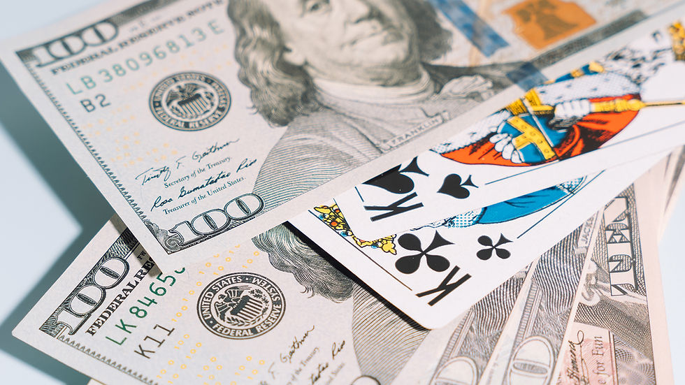 Playing cards with kings of spades and clubs atop several 100-dollar bills. The scene suggests a theme of gambling or wealth.