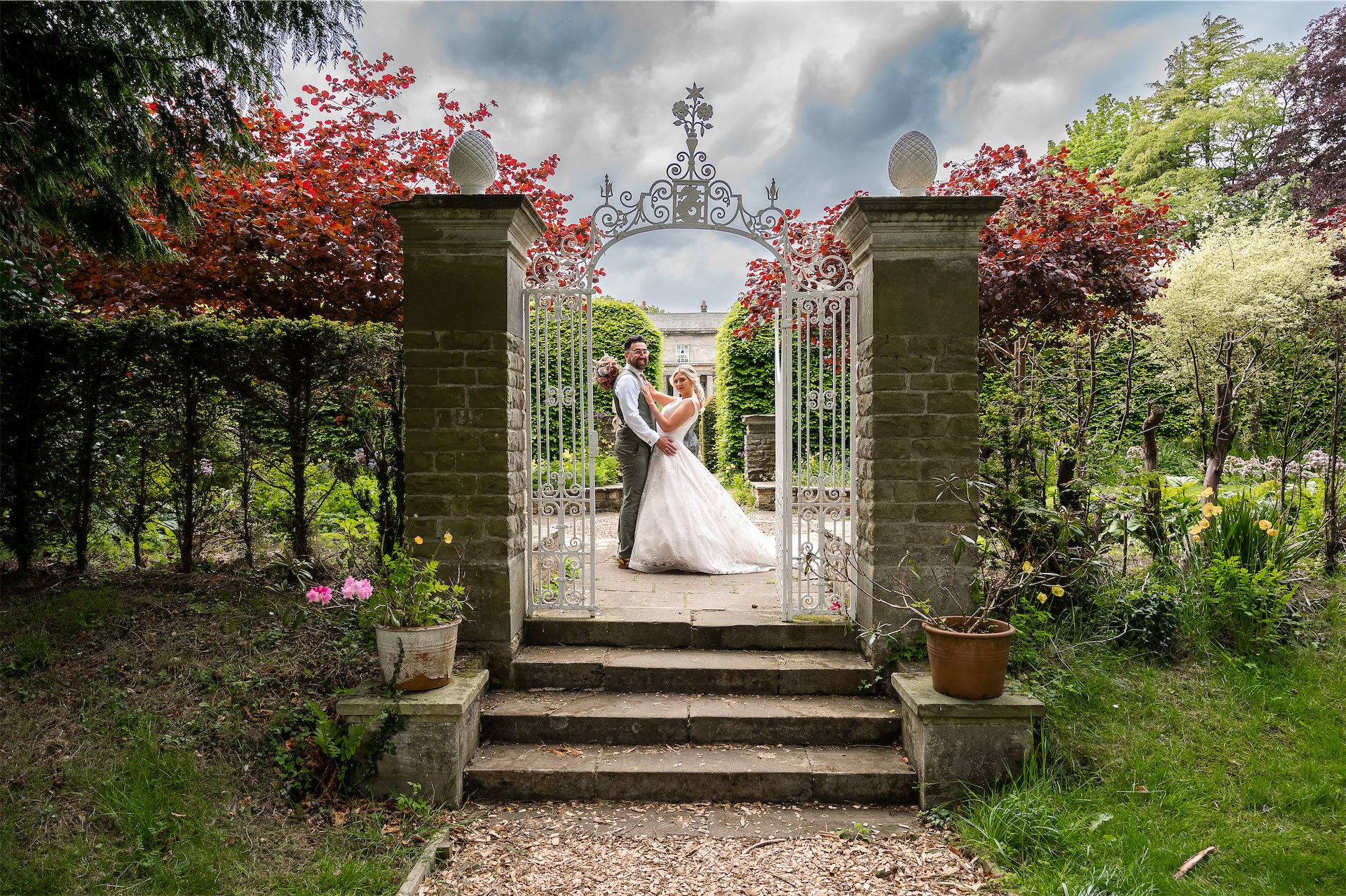Bride and groom pose at ornate garden gate