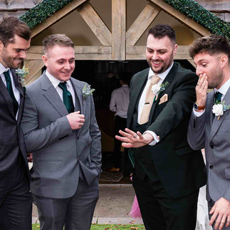 Groom showing ring to groomsmen outside South Causey Inn