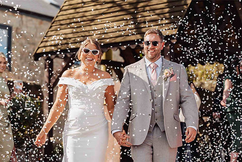 Happy couple exits ceremony, confetti falling