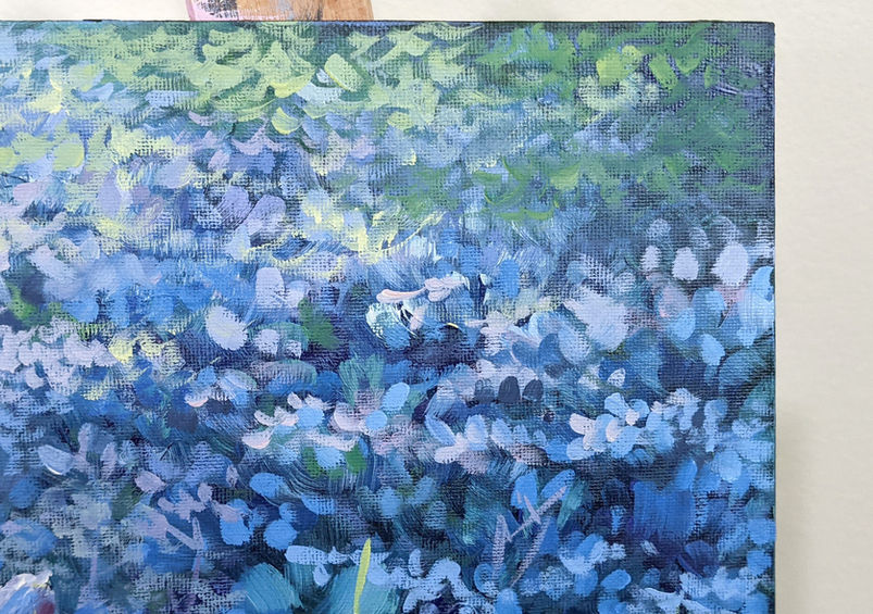 Close-up detail from oil painting "Where the Fairies Live" by Catherine Snowstorm showing the dense carpet of small blue aubrieta flowers in the upper right of the composition. Loose individual brushstrokes build up the mass of tiny blossoms in blue, light blue, and white against the deep blue-teal ground — the blue imprimatura showing through gives the shadows natural coolness. Green and teal stems weave through the mass. The canvas corner and easel are visible. Textured brushwork botanical fine art, macro floral painting detail.