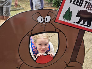 girl looking through a bear-shaped photo cutout board