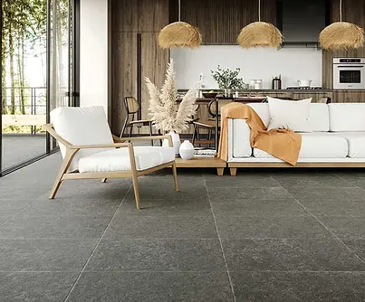 Gezellige woonkamer met grote keramische vloertegels in blauwe steen look en warme natuurlijke materialen.