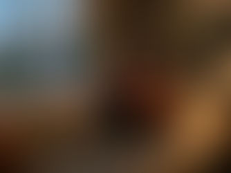 Woman sitting alone on a couch in a softly lit living room, looking out the window with a phone placed beside her, expressing loneliness and emotional withdrawal.