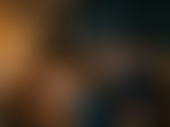 Couple sitting close together on a couch at home smiling while looking at a phone together