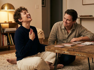 Couple laughing while playing a card-based questions game at home, creating a relaxed and engaging conversation