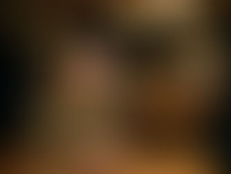 Woman sitting alone at a restaurant table with a glass of wine, appearing thoughtful and emotionally distant in a dimly lit setting.