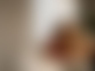 Man and woman sitting on a couch reading a book together in a cozy living room with warm sunlight.