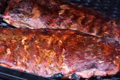 Barbecue ribs cooking on a grill with a caramelized glaze