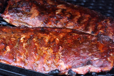 Barbecue ribs cooking on a grill with a caramelized glaze