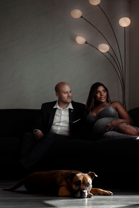 Couple posing with their dog on a living room sofa