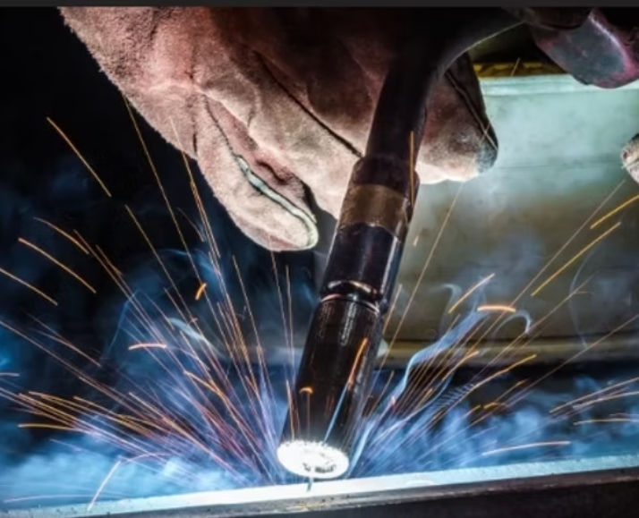 "MIG welding South Africa – Swift Skills Academy Cape Town accredited training with MERSETA & QCTO pathways. Industrial welder performing metal inert gas welding on steel pipe using PPE, gloves, and welding helmet under supervisor oversight for OHSA compliance, Red Seal certification, B‑BBEE skills development credits, and corporate workforce empowerment."