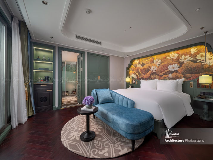Nội thất phòng deluxe tại Tonkin Luxury Boutique Hotel Hà Nội với sofa xanh và tranh đầu giường