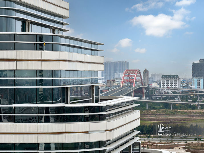 Góc nhìn tòa nhà cao tầng với mặt đứng kính cong và cảnh quan đô thị phía sau.