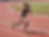 Sports photography of a female athlete with prosthetic legs sprinting on a red track. Her determined expression and powerful stride highlight her athleticism.