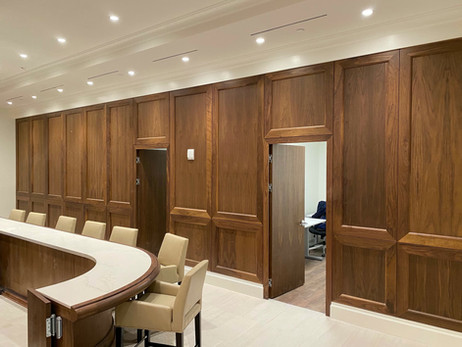 a room with a round table and chairs and wood paneled walls