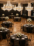 Elegant ballroom with chandeliers and set dining tables.