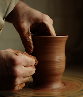 Unknown master forming jar from wet clay piece in pottery. Unrecognized clay artist modeli