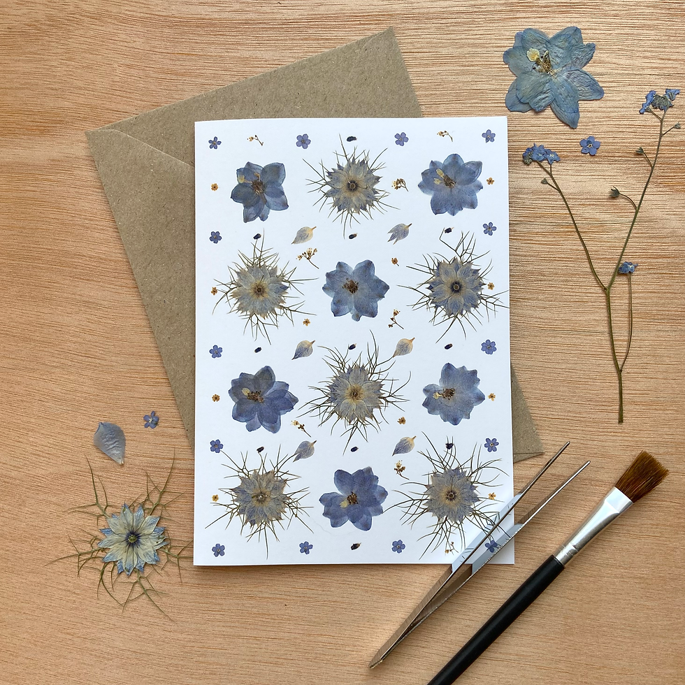 Blue printed pressed flower greetings card on art desk