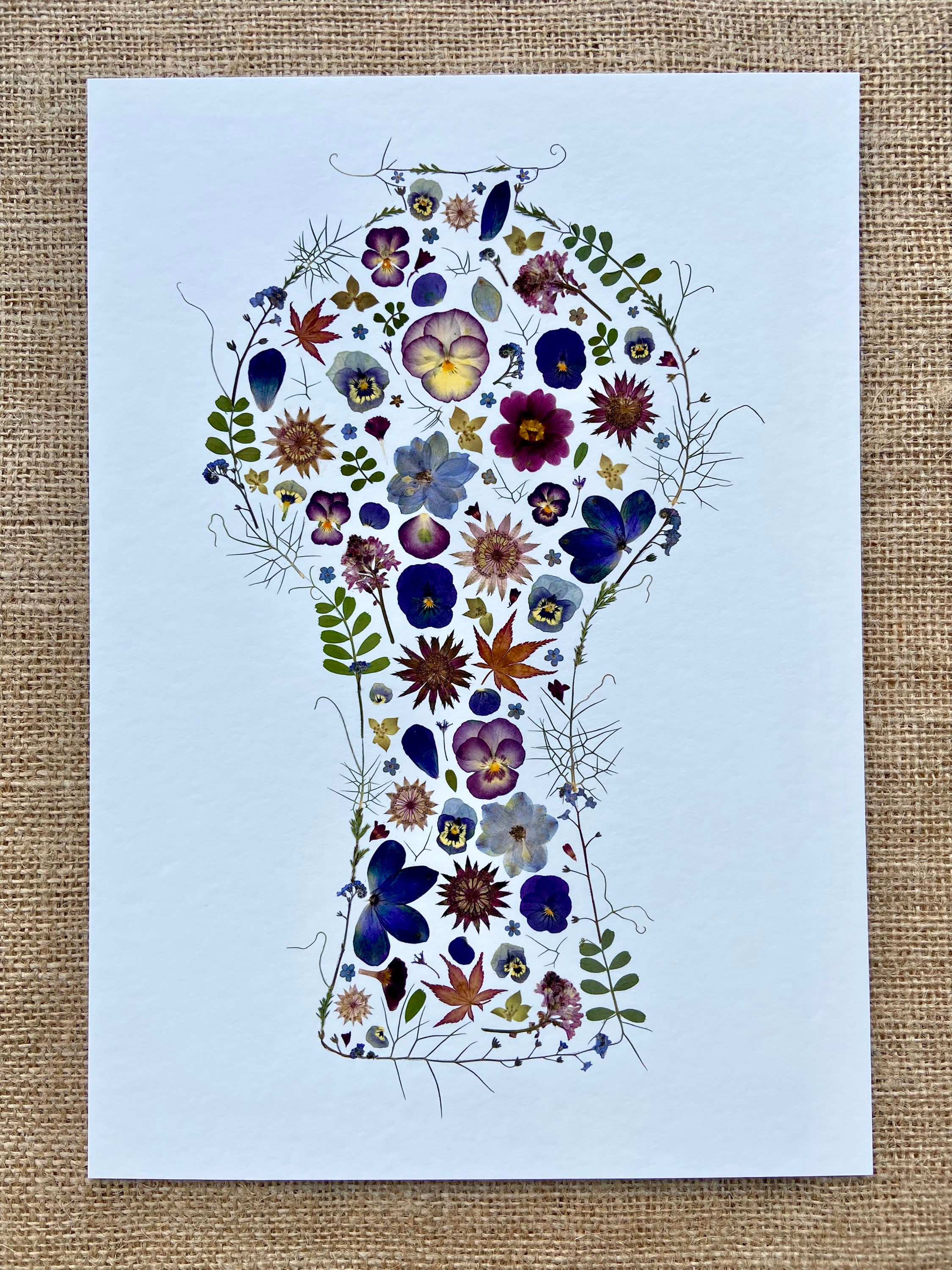 A giclee print of a vase shape, created with blue, purple and violet pressed flowers