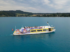 Drohenaufnahme von einem Schiff am blauen Attersee
