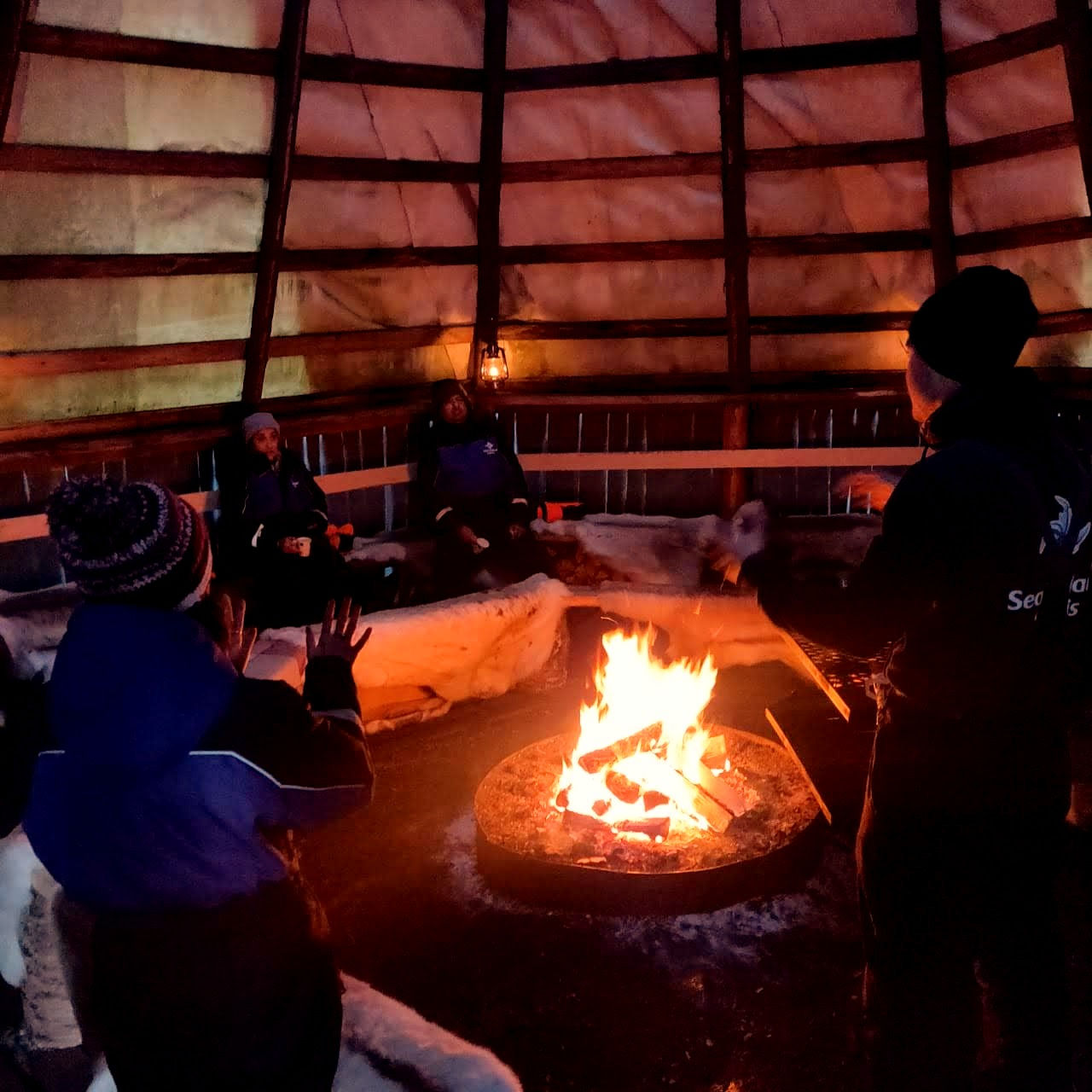 Kuta, a Finnish Log Hut with fire burning inside and we all are warming ourselves after the snowshoe activity