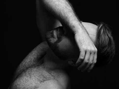 foto artística do ator em preto e branco, com o corpo reclinado para trás, braço direito sobre seus olhos.
