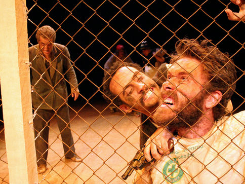 Gustavo Valezzi, interpretando Chicão, sendo empurrado contra um alambrado, por outro ator, Vinícius Carvalho.