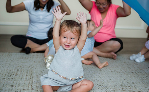 Baby and caregivers participating in a private at-home toddler music class with group interaction and movement