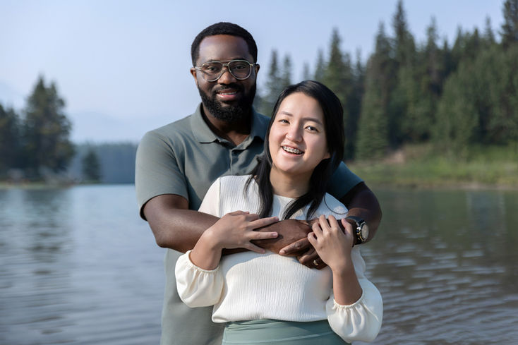 Couple embracing beside Two Jack Lake during a family mini session in Banff National Park.