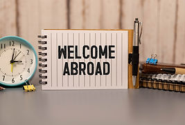 WORKING ABROAD text written on yellow paper with notebook.jpg