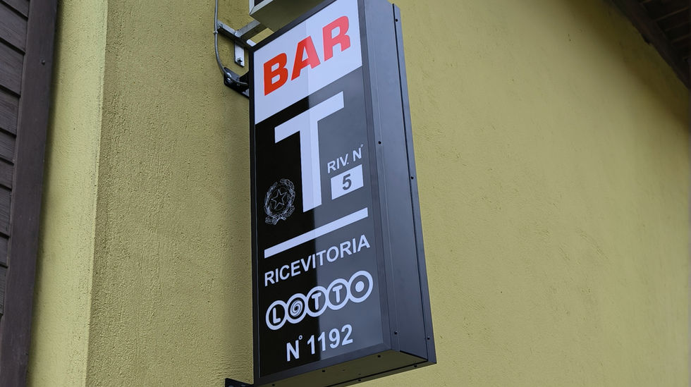 Insegna per tabaccheria, con lastra luminosa decorata da adesivi neri e rossi.