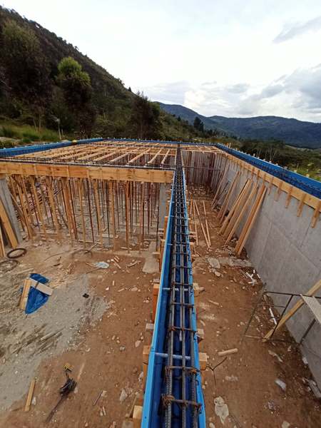 Encofrado de losa con apuntalamiento y armado de vigas, junto a muros de concreto, en obra en Oxapampa