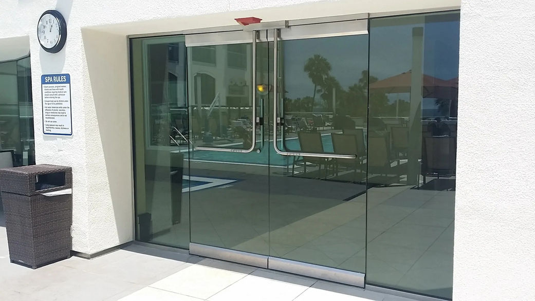 Glass doors leading to a pool area with a clock and informational sign outside