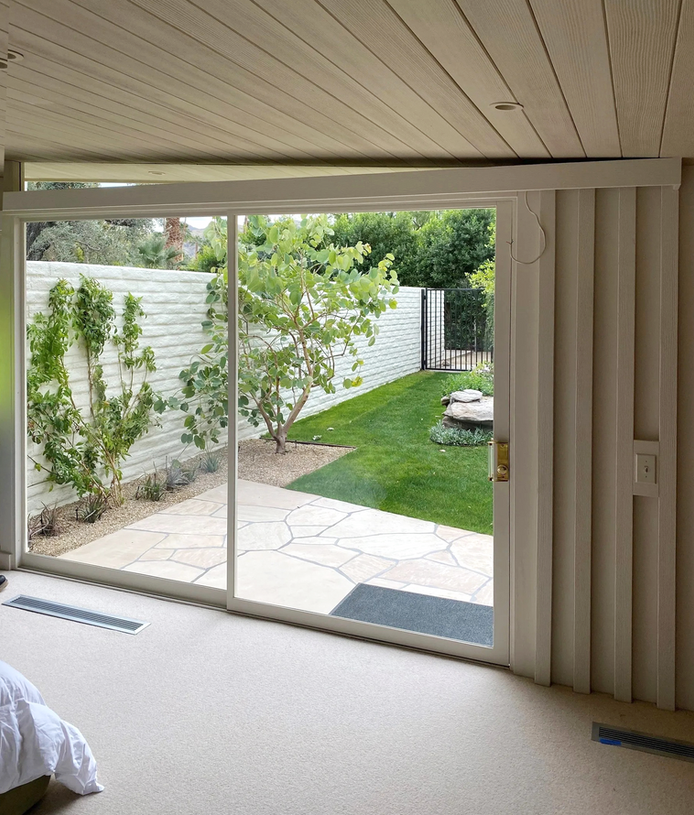 Patio view through sliding glass door with a green backyard and trees