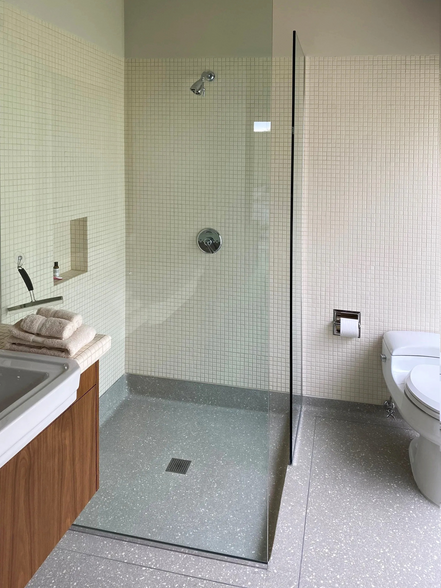 Modern bathroom with a glass shower, toilet, sink, and neutral color scheme.