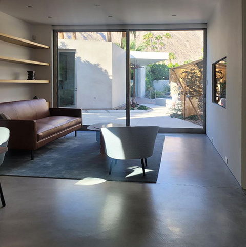 Modern living room with leather couch, chair, and large window view.