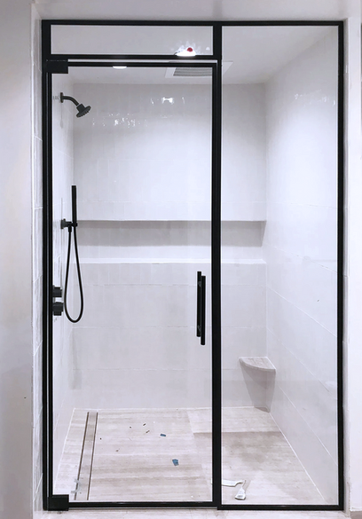 Modern shower with black frame and glass door in white tiled bathroom