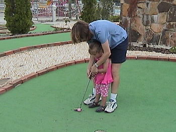 A [arent helping a child feel how to putt