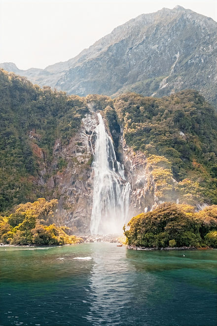 Waterfall cascading down a forested cliff in Fiordland