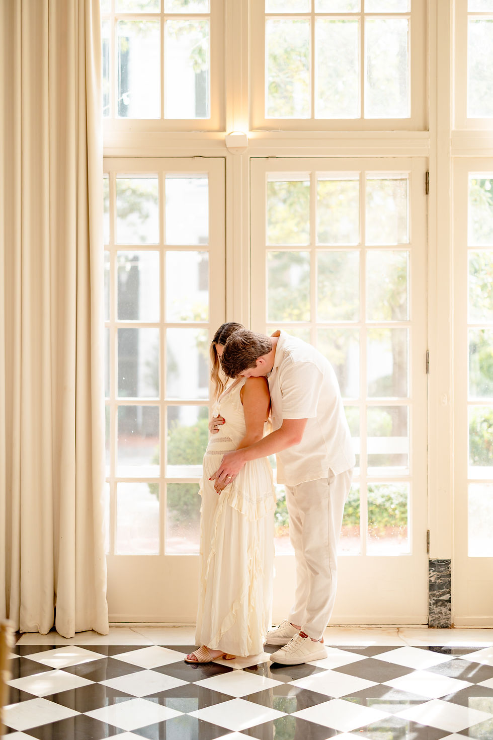 Dad to be kissing mom to be in the Duke Mansion Solarium in Charlotte NC