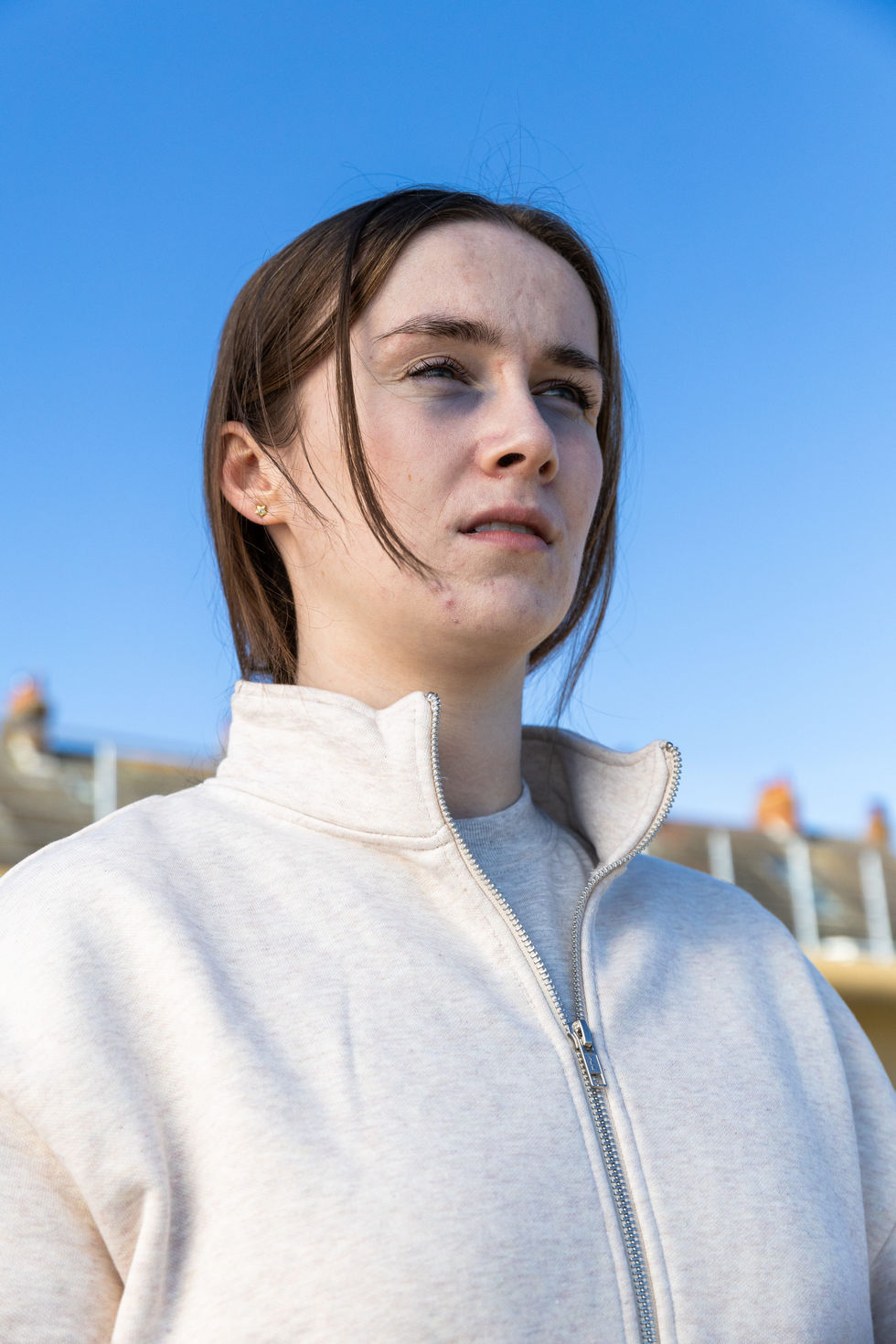 A young woman stands, looking out to sea.