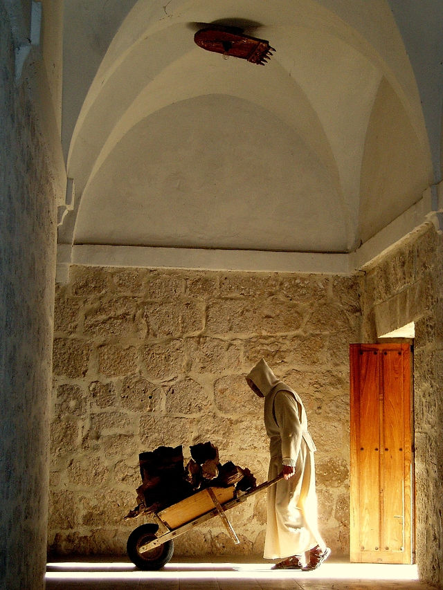 Un moine dans sa tunique blanche pousse une brouette au sein du monastère. 