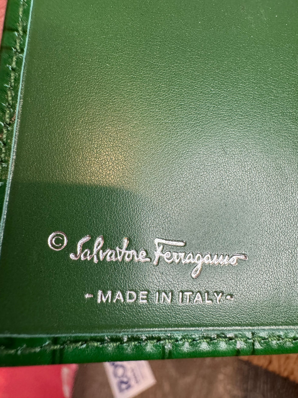 Thumbnail: Green Salvatore Ferragamo Gancini wallet featuring an embossed logo pattern.