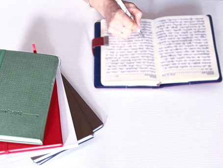 mano che scrive su diario, altri diari e quaderni di lato - pratica di journaling