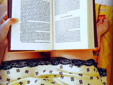 Una ragazza che legge un libro seduta sul letto