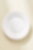White ceramic plate with slightly irregular edges on a beige background. Speckled rim detail, minimalistic and clean design.