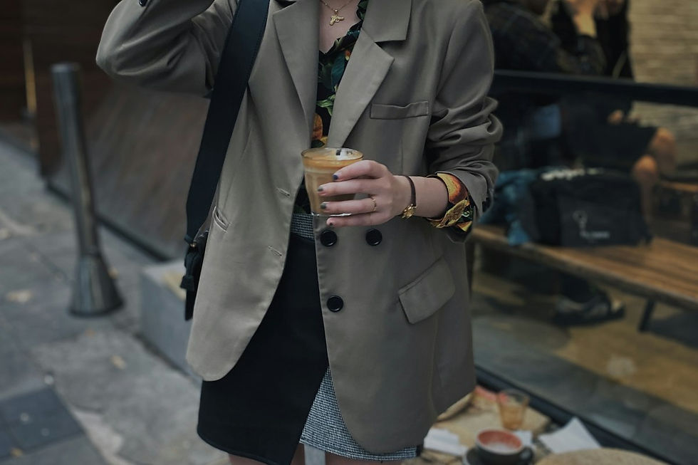 Woman in an oversized khaki blazer holding a coffee