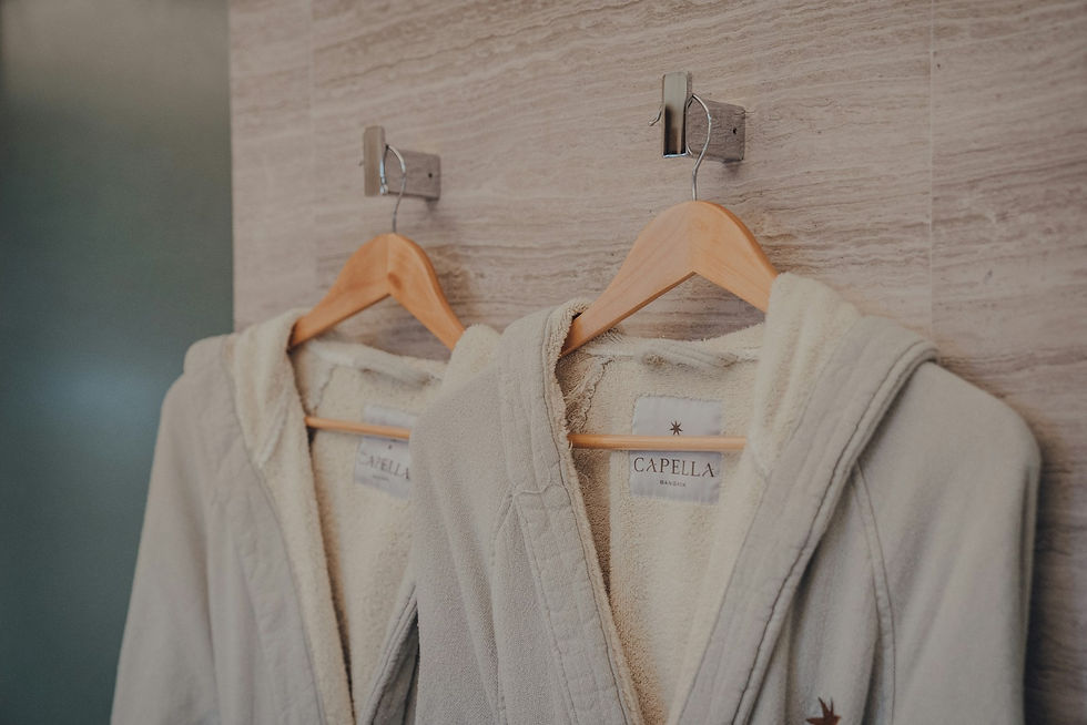 Two white plush robes hanging on wooden hangers