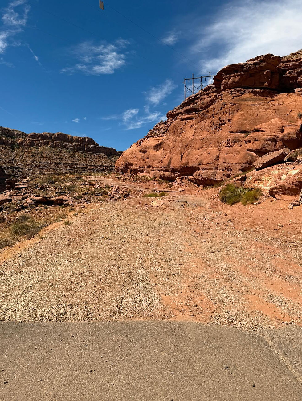 Poison Spider Mesa road transitioning from pavement to a rough gravel off-road trail near Moab, Utah.